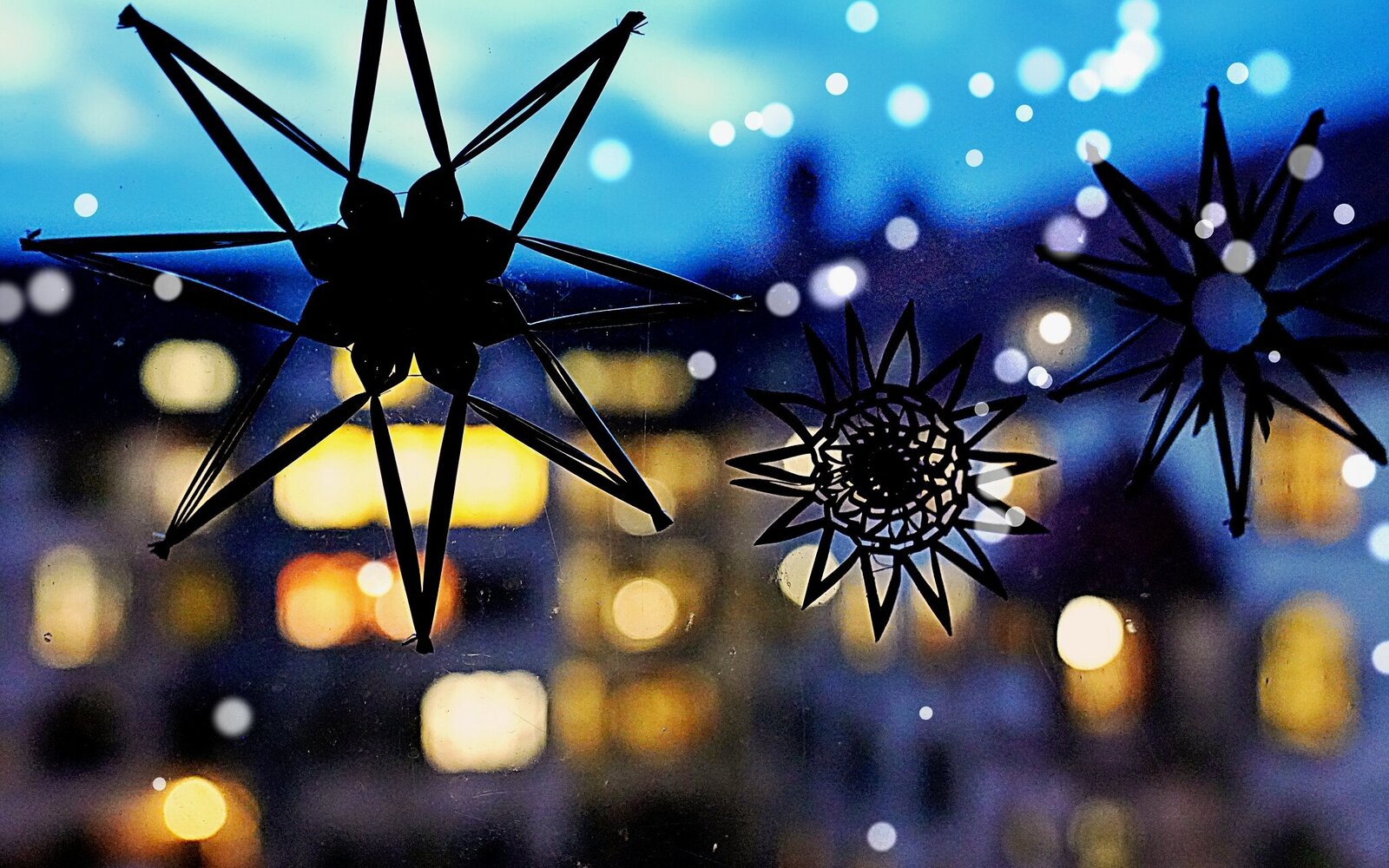 Zu sehen sind Strohsterne am Fenster, im Hintergrund der Altbau der Hochschule