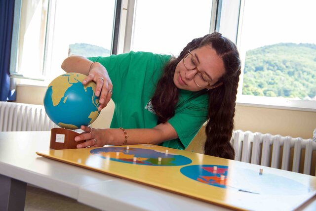 Eine Studentin beugt sich über einen barrierearmen Globus.