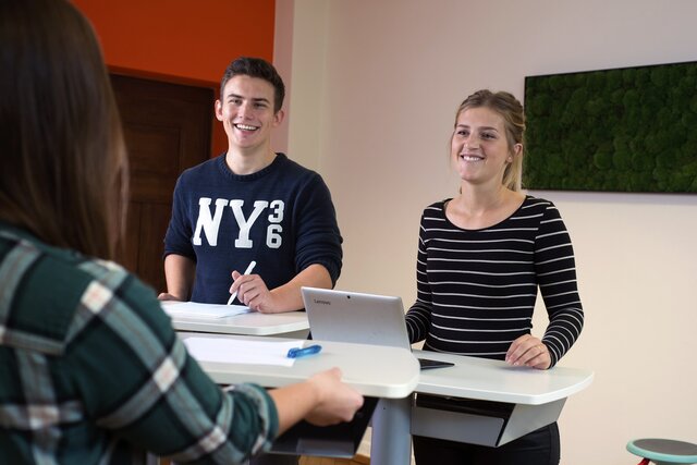 Mehrere Personen stehen an Tischen.