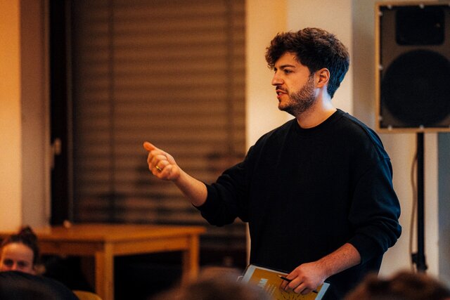 Zu sehen ist Moderator Max Wetterauer beim Science Slam der PH Heidelberg 2024.