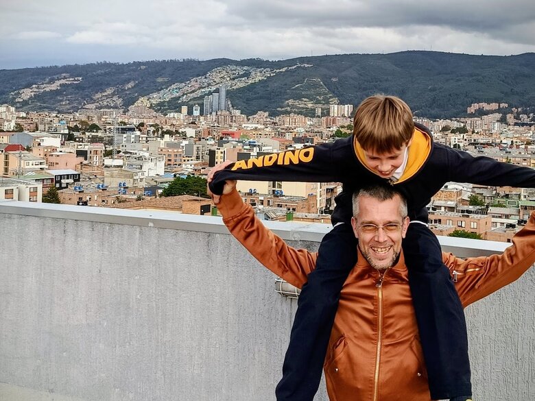 Zu sehen ist der Sonderpädagogikstudent Julian mit seinem Sohn Lucas auf den Schultern vor der Metropole Bogota