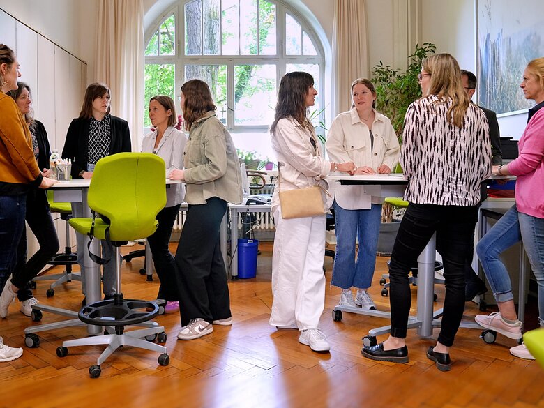 Eine große Gruppe an Menschen steht im SSC an den Stehtischen und unterhält sich.