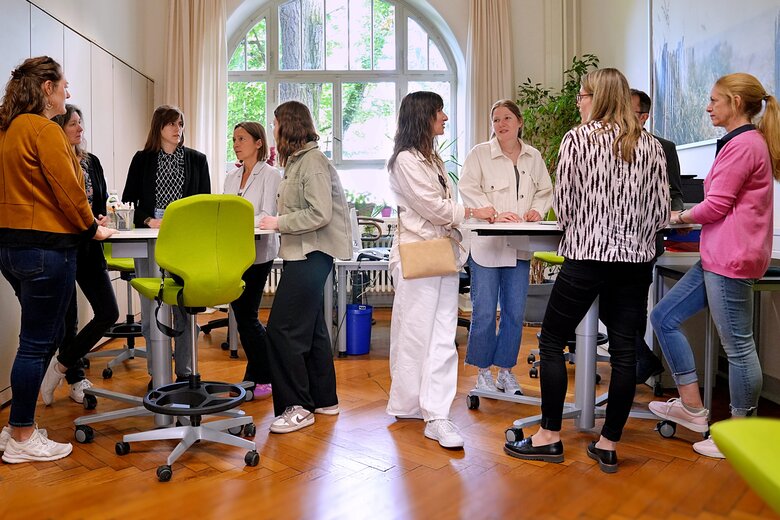 Im Rahmen internationaler Lehre steht eine große Gruppe an Menschen im SSC an den Stehtischen und unterhält sich.  