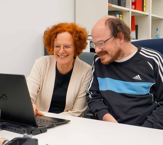 Ute Raible und Thilo Krahnke sitzen am Schriebtisch vor einem Laptop. 