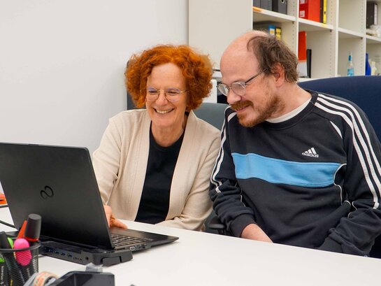 Ute Raible und Thilo Krahnke sitzen am Schriebtisch vor einem Laptop. 