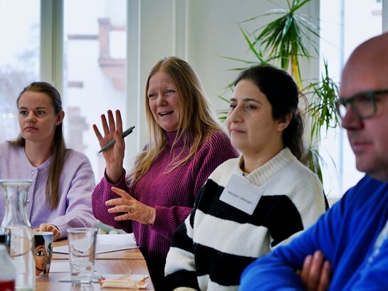 Das Foto zeigt verschiedene Menschen im Gespräch.