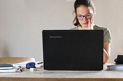 Frau an einem Laptop sitzend.