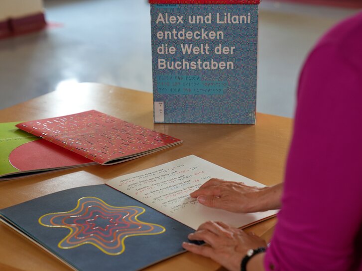 Zu sehen ist ein aufgeschlagenes Braille-Buch. 