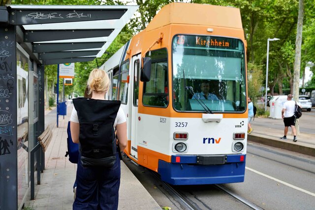 Eine Frau mit Rucksack läuft auf eine Straßenbahn in Richtung Kirchheim zu.