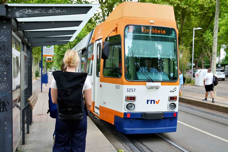 Eine Frau mit Rucksack läuft auf eine Straßenbahn in Richtung Kirchheim zu.