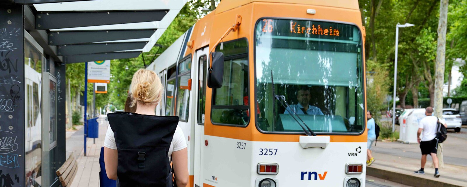 Eine Frau mit Rucksack läuft auf eine Straßenbahn in Richtung Kirchheim zu.