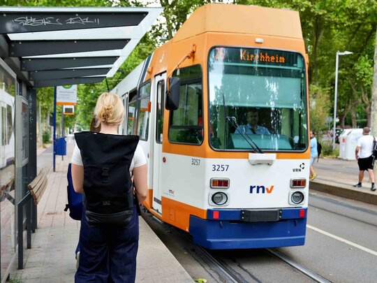 Eine Frau mit Rucksack läuft auf eine Straßenbahn in Richtung Kirchheim zu.