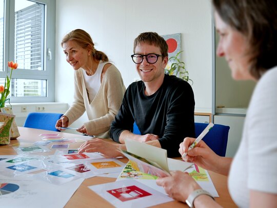 Zu sehen ist Herr Rued am Tisch sitzend mit Kolleg:innen
