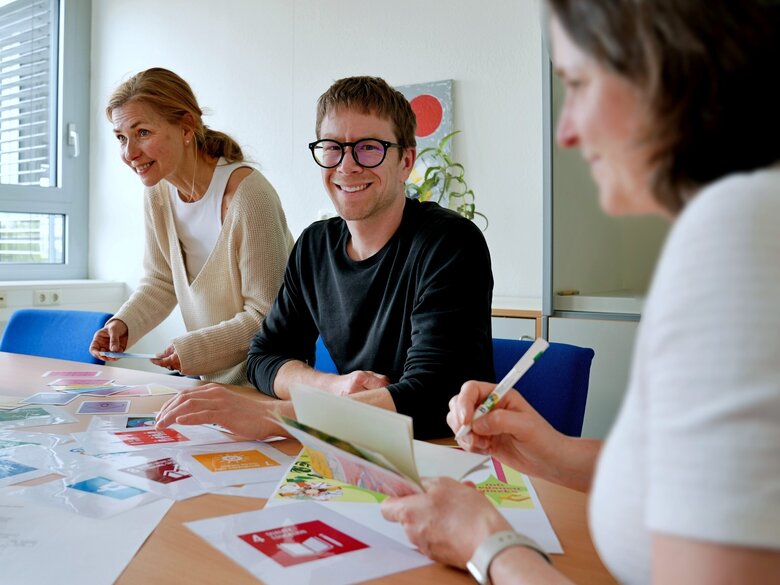 Zu sehen ist Herr Rued am Tisch sitzend mit Kolleg:innen