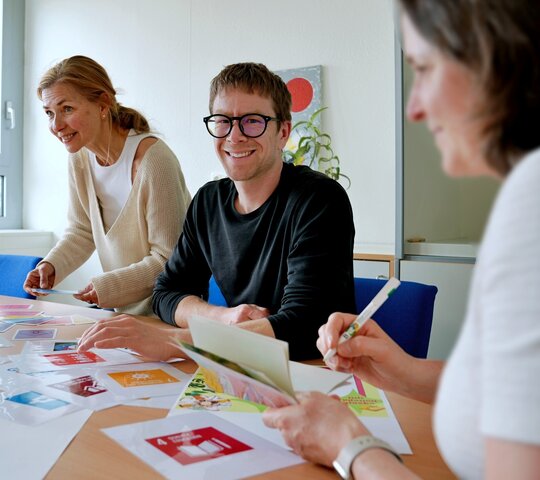 Zu sehen ist Herr Rued am Tisch sitzend mit Kolleg:innen