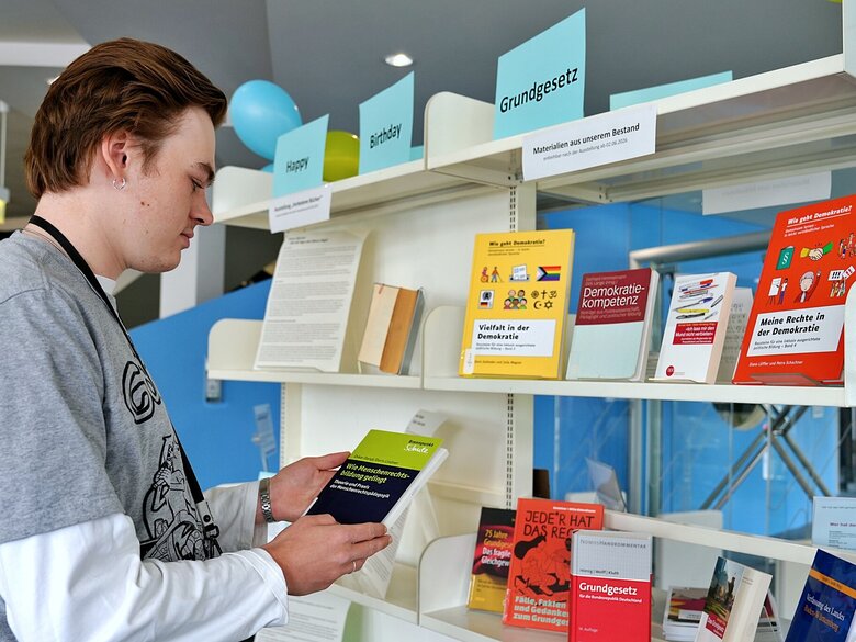 Zu sehen ist Ein Besucher der Ausstellung, der in einem Buch liest