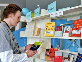 Zu sehen ist Ein Besucher der Ausstellung, der in einem Buch liest