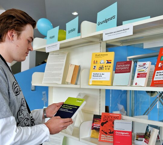 Zu sehen ist Ein Besucher der Ausstellung, der in einem Buch liest