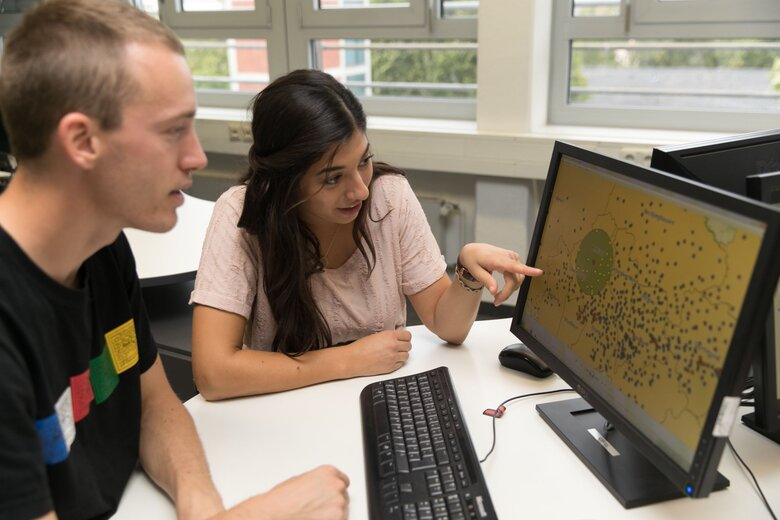 Zwei Personen vor einem Bildschirm auf dem GEographische Daten zu sehen sind