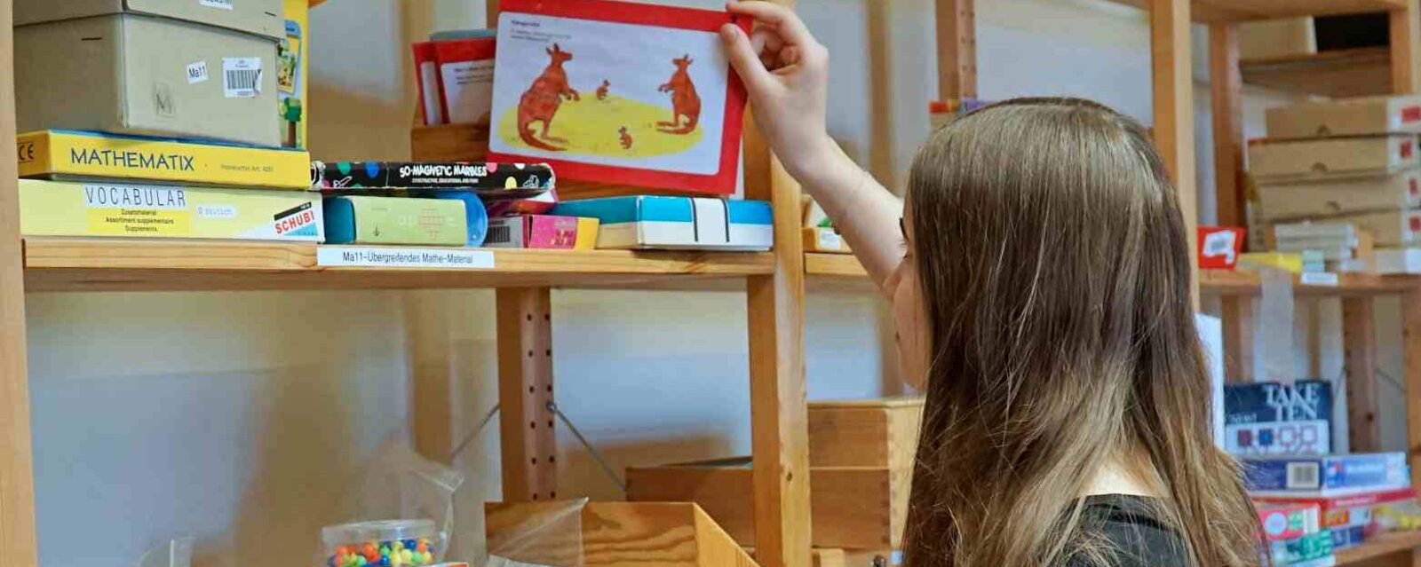 Zu sehen ist eine Studentin an einem Regal.