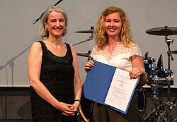 Das Foto zeigt eine Frau mit Michael-Raubal-Preis für herausragende Abschlussarbeiten und eine weitere Frau.
