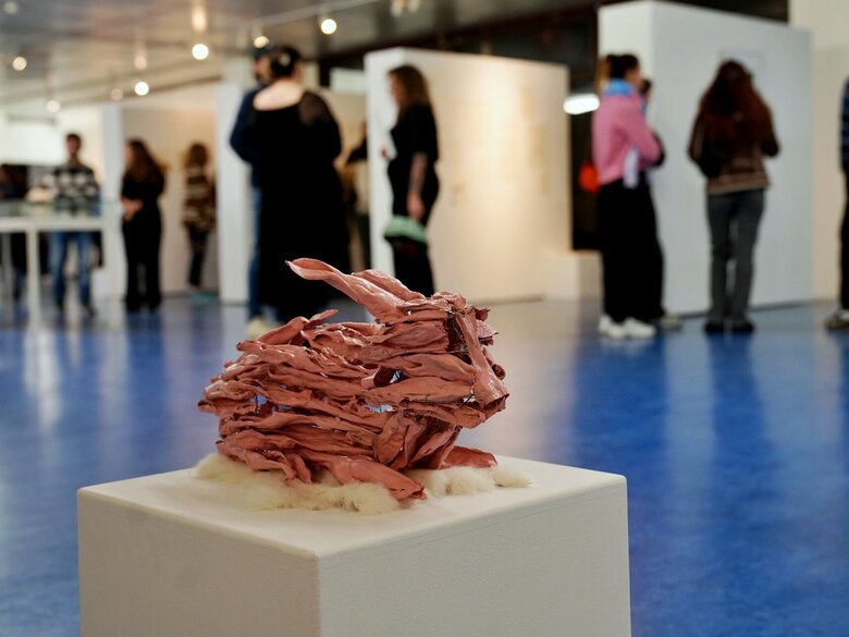 Zu sehen ist eine rosafarbene Hasenplastik und im Hintergrund Besucher:innen der Ausstellung