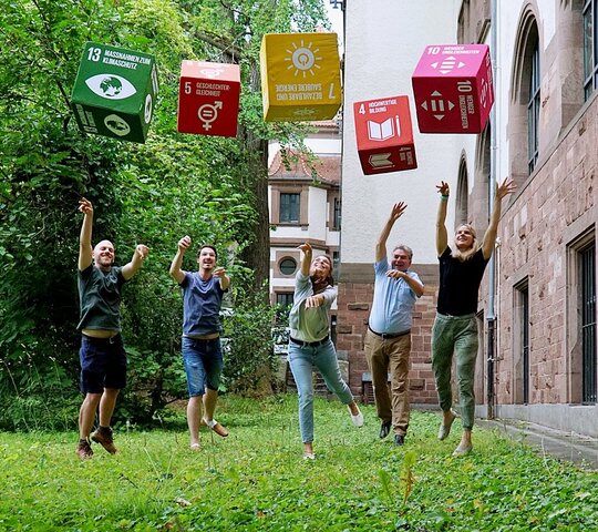 Das Foto zeigt Menschen, die Würfel mit aufgedruckten Nachhaltigkeitszielen werfen.