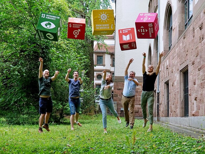 Das Foto zeigt Menschen, die Würfel mit aufgedruckten Nachhaltigkeitszielen werfen.