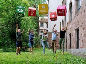 Das Foto zeigt Menschen, die Würfel mit aufgedruckten Nachhaltigkeitszielen werfen.