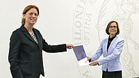 Das Bild zeigt links Bildungsministerin Karin Prien und rechts CAU-Präsidentin Professorin Simone Fulda. Beide halte eineUrkundenmappe zwischen sich. Aufgenommen hat das Bild Kai-Ole Nissen.