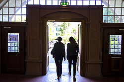 Das Foto zeigt zwei Personen in Rückenansicht beim Verlassen des Foyers der PH Heidelberg.