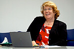 Das Bild zeigt Karin Terfloth. Sie sitzt an einem Tisch. Vor ihr ein Laptop. Sie lacht. Copyright: PH Heidelberg