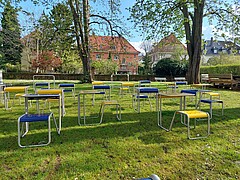 Keplerhof. Abgebildet ist die Außenfläche im Altbauhof der PH. Auf einer Rasenfläche unter alten Bäumen stehen Sitzmöbel (Einzelsitzplätze).