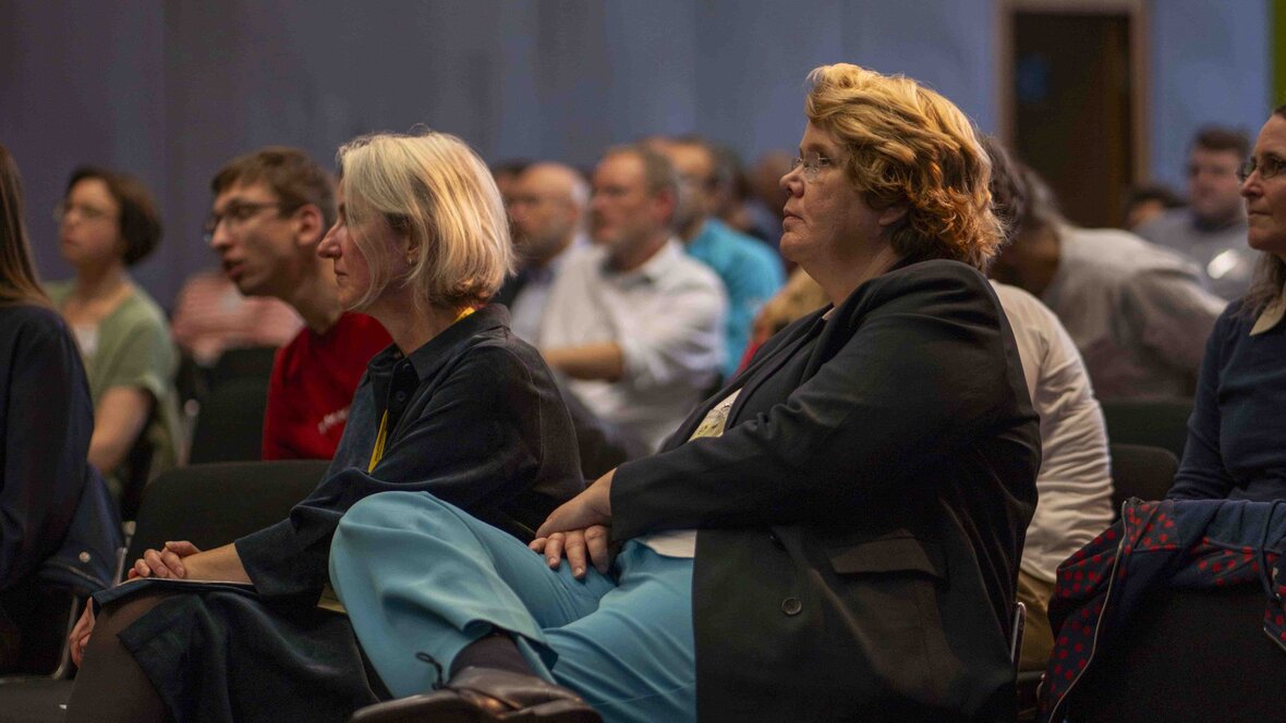 Das Bild zeigt die professoralen Leiterinnen des AW-ZIB: Karin Terfloth und Vera Heyl. Beide sitzen auf Stühlen und verfolgen einen Beitrag.