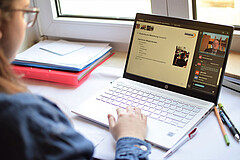 Das Foto zeigt eine Frau am Schreibtisch mit ihrem Laptop und Stiften.