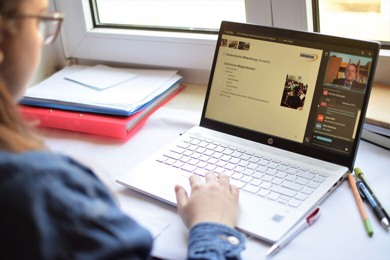Das Foto zeigt eine Frau am Schreibtisch mit ihrem Laptop und Stiften.