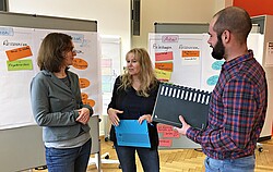 Zwei Frauen und einen Mann bei einem moderiertem Workshop zu Stressfaktoren und Ressourcen am Arbeitsplatz .