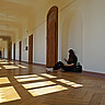 Das Symbolbild zeigt ein junges Mädchen, das im leeren Flur der Hochschule auf dem Boden sitzt und auf ihr Handy schaut. Copyright: Pädagogische Hochschule Heidelberg