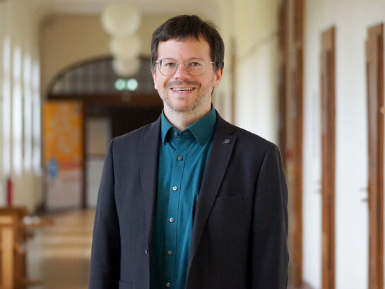 Porträaufnahme von Florian Kollmann im Flur des Altbaus der Pädagogischen Hochschule Heidelberg.