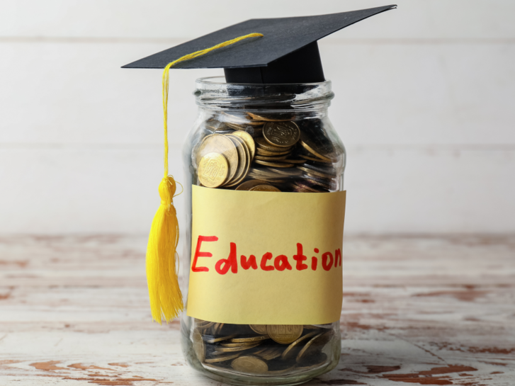 Ein Glas mit Münzgeld und einem Absolvet:innenhut, auf dem Glas steht "education"