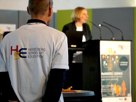 Das Foto zeigt die Rücksicht einer Person, welche ein T-Shirt von der HSE trägt.