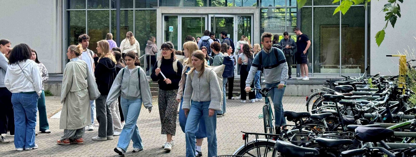 Auf dem Bild sind mehrere Personen vor dem Hörsaalgebäude der Neuen PH zu sehen.