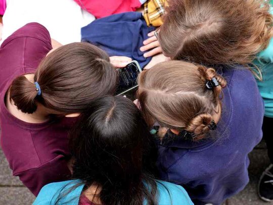 Kinder stecken die Köpfe zusammen. Das Bild ist aus der Vogelperspektive aufgenommen.