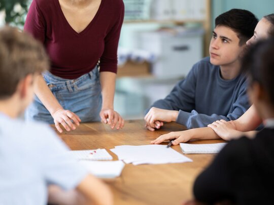 Lehrperson im Gespräch mit Schüler:innen
