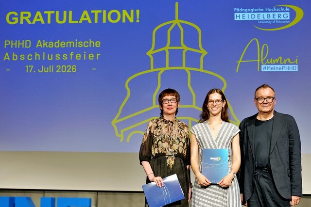 Zu sehen sind Absolvent:innen der PHHD, die sich mit ihren Urkundenmappen auf der Bühne zum Gruppenfoto aufgestellt haben.