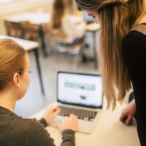 Zwei jungen Frauen sitzen vor einem Laptop.
