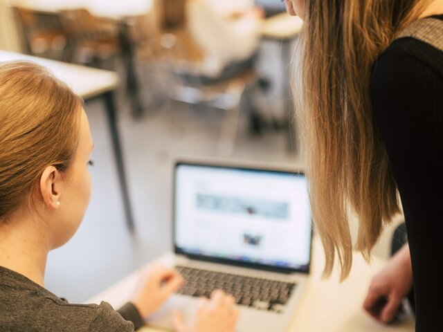 Zwei jungen Frauen sitzen vor einem Laptop.