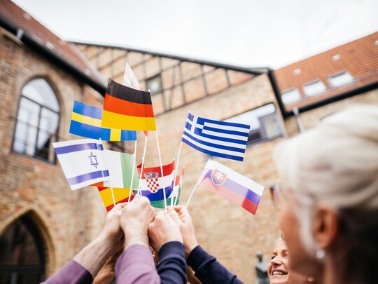 Eine Personengruppe hält Länderflaggen in die Luft