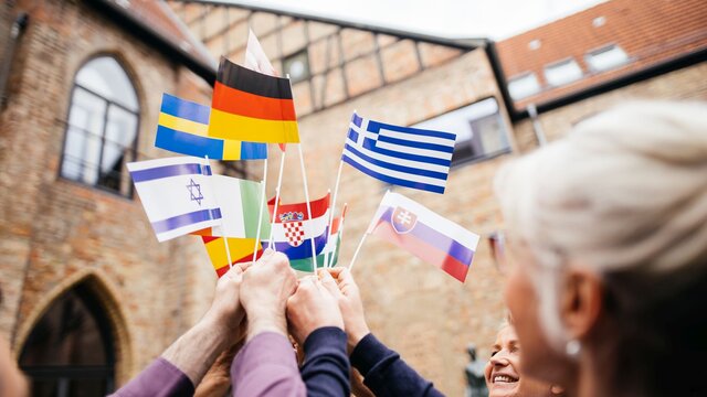 Eine Personengruppe hält Länderflaggen in die Luft
