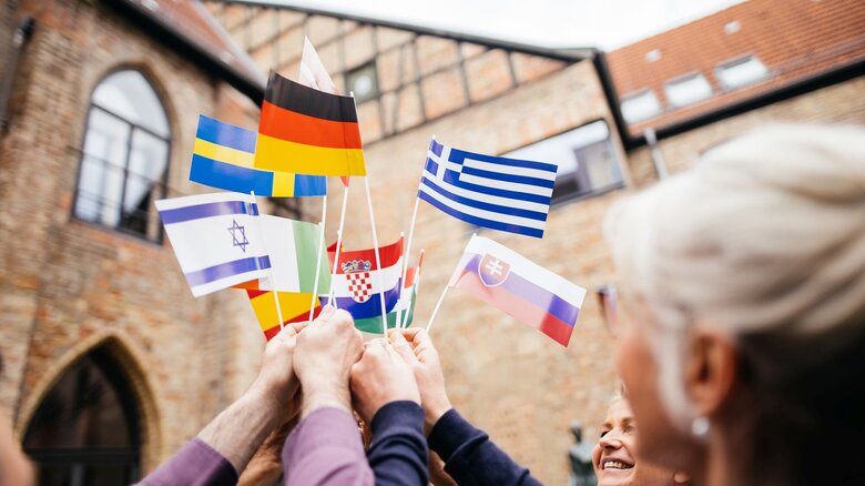 Eine Personengruppe hält Länderflaggen in die Luft